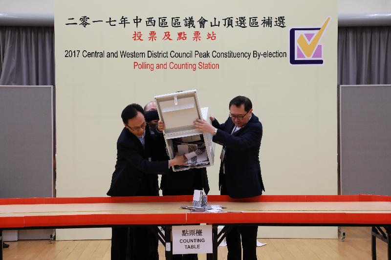 The Electoral Affairs Commission Chairman, Mr Justice Barnabas Fung Wah (right), and the Secretary for Constitutional and Mainland Affairs, Mr Patrick Nip (left), empty a ballot box at the counting station at Hong Kong Park Sports Centre for the Central and Western District Council Peak Constituency by-election last night (November 26).