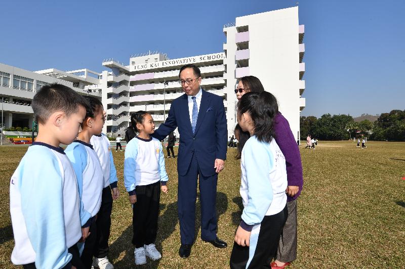 The Secretary for Innovation and Technology, Mr Nicholas W Yang (fifth left), chats with students on the grass pitch during his visit to Fung Kai Innovative School today (December 11).