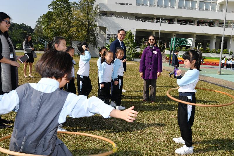 Accompanied by the Principal of Fung Kai Innovative School, Ms Yvonne Li (back row, first right), the Secretary for Innovation and Technology, Mr Nicholas W Yang (back row, second right), watches students conducting activities on the grass pitch today (December 11).