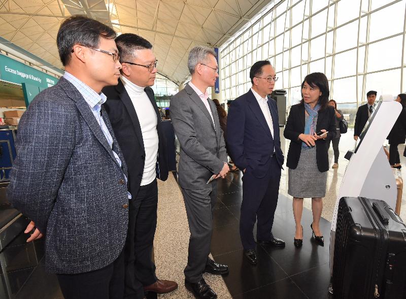创新及科技局局长杨伟雄（右二）今日（十二月十四日）在香港国际机场听取香港机场管理局机场运行副总监张李佳蕙（右一）介绍自助登记服务。