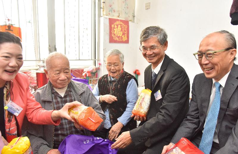 The Secretary for Labour and Welfare, Dr Law Chi-kwong, visited Kwun Tong District today (December 15) to pay home visits. Photo shows Dr Law (second right) presenting an elderly couple with a gift pack.