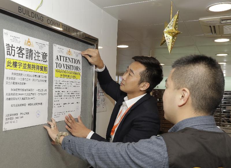 Officers of the Office of the Licensing Authority post advisory notices in the lobby of a residential block in City One Shatin, alerting visitors that there are no licensed guesthouses in the building.