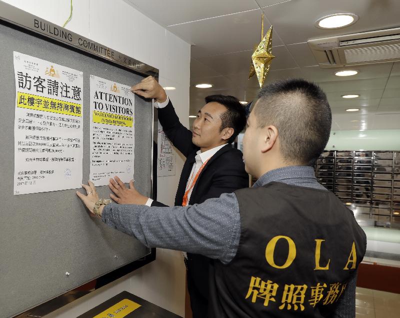 The Office of the Licensing Authority (OLA) of the Home Affairs Department stepped up law enforcement actions during the Christmas and New Year holidays to combat unlicensed guesthouses. Photo shows  OLA officers posting advisory notices in the lobby of a residential block, alerting visitors that there are no licensed guesthouses in the building.