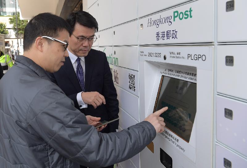 The Secretary for Commerce and Economic Development, Mr Edward Yau (right), tours the iPostal Station and learns about the operation of the self-service locker suite to collect mail items during his visit to the General Post Office today (February 6).