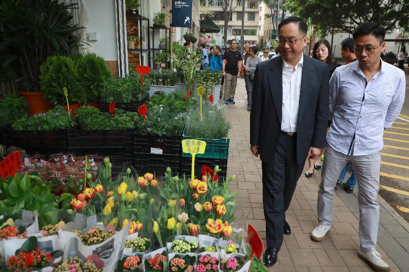 The Secretary for Innovation and Technology, Mr Nicholas W Yang (left), accompanied by the Chairman of the Yau Tsim Mong District Council, Mr Chris Ip (right), drops in at Flower Market Road in Prince Edward today (March 26) to learn about the floral and horticultural retail business there.