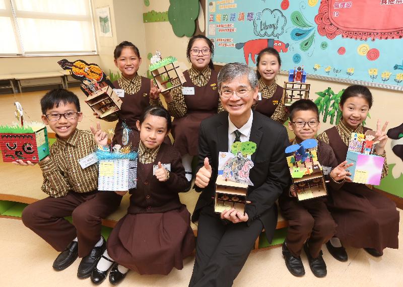 The Secretary for Labour and Welfare, Dr Law Chi-kwong, visited Wong Tai Sin District today (April 10) and called at Canossa Primary School (San Po Kong). Photo shows Dr Law (front row, centre) with students and some of their work.