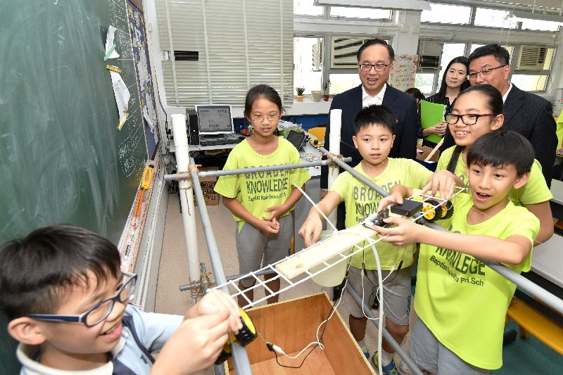 The Secretary for Innovation and Technology, Mr Nicholas W Yang (back row, left), watches students participating in self-directed learning activities at Baptist Rainbow Primary School today (May 17). Joining the visit are the Chairman of the Wong Tai Sin District Council, Mr Li Tak-hong (back row, right), and the District Officer (Wong Tai Sin), Ms Annie Kong (back row, centre).