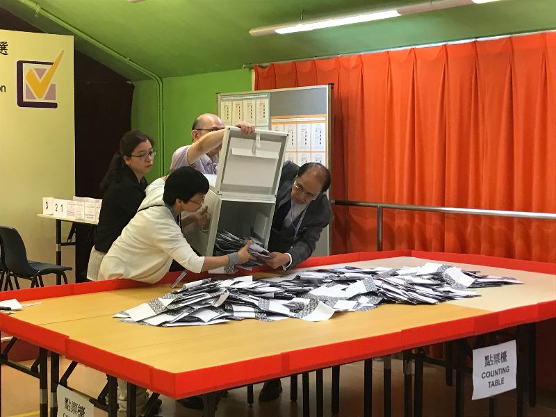 选举管理委员会委员陆贻信资深大律师（右一）昨晚（六月十日）在东区区议会佳晓选区补选设于香港中华基督教青年会──柴湾会所的点票站倒出票箱中的选票。
