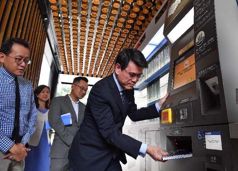 The Secretary for Commerce and Economic Development, Mr Edward Yau (first right), today (June 14) visits the self-service library station located at the Island East Sports Centre Sitting-out Area during his visit to Eastern District to try using the round-the-clock services of borrowing and return of library materials.