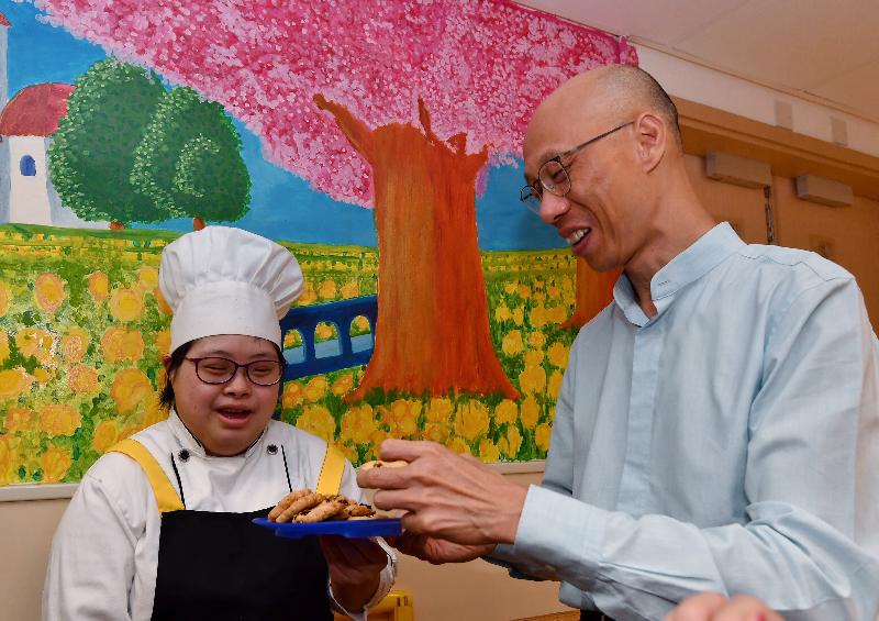 The Secretary for the Environment, Mr Wong Kam-sing (right), visits Jockey Club Endeavour Workshop + Albert Wu Rainbow Workshop operated by St James' Settlement in Wan Chai today (June 22) and praises people with rehabilitation service needs for making delicious cookies with soybean paste.