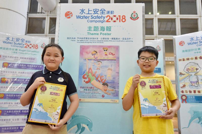 Awards for the water safety slogan and poster design competitions organised by the Leisure and Cultural Services Department and the Hong Kong Life Saving Society were presented today (June 23). Pictured with her winning entry is Yip Hiu-ching (left), champion of the primary school section in the Water Safety Poster Design Competition, and Li Kin-lok (right), champion of the primary school section in the Water Safety Slogan Competition.