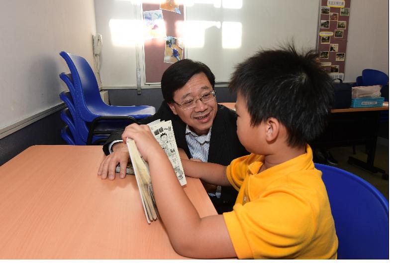 During his visit to the Ngau Tau Kok Youth Integrated Service Centre of Kwun Tong Methodist Social Service this afternoon (June 26), the Secretary for Security, Mr John Lee (left), chats with a child who is reading in the children's activity room.