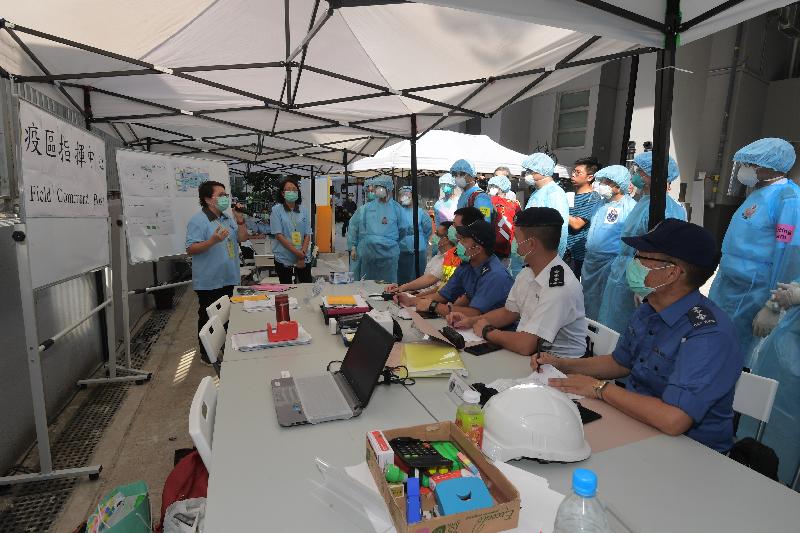 The Centre for Health Protection of the Department of Health, in collaboration with other government departments and organisations, today (June 27) held a public health exercise code-named "Sunstone" at a newly built residential building to test the Government's response to a novel disease called "Disease X". Photo shows representatives from various government departments and organisations being briefed on the situation and necessary actions at the field command post set up at scene.
