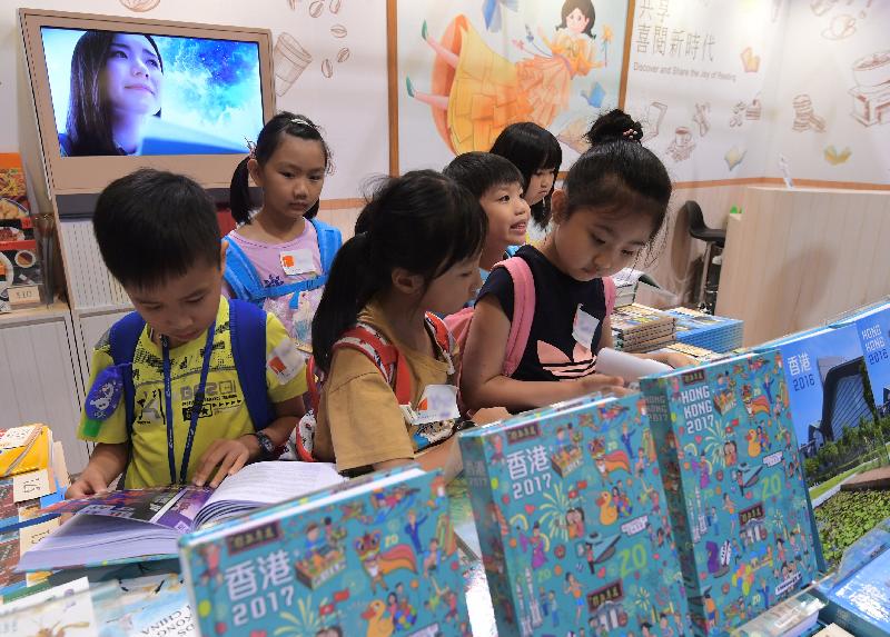 政府新聞處以「共享‧喜閱新時代」為主題，參與今日（七月十八日）至七月二十四日舉行的香港書展。圖示兒童閱覽新一期政府年報《香港2017》的圖片和天文趣味書刊。