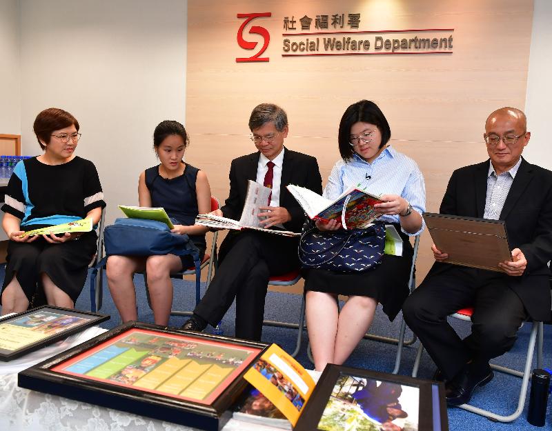 The Secretary for Labour and Welfare, Dr Law Chi-kwong, visited the Adoption Unit of the Social Welfare Department this morning (July 19). Photo shows Dr Law (centre) reading a life book prepared by adoptive parents on the lives of their adoptive children. Two secondary school students (second left and second right) enrolled under the "Be a Government Official for a Day" programme to shadow the Secretary also joined the visit.