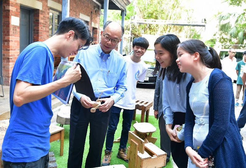 The Secretary for Transport and Housing, Mr Frank Chan Fan (second left), visited the Warehouse Teenage Club in Southern District with two secondary school students participating in the "Be a Government Official for a Day" programme today (July 25). A woodwork instructor shows them the work created by members of the centre.