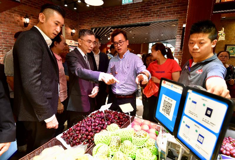 The Secretary for Financial Services and the Treasury, Mr James Lau (second left), visits Kai Tin Market in Lam Tin today (July 27) and chats with a stall operator to learn more about customers' use of mobile payment.