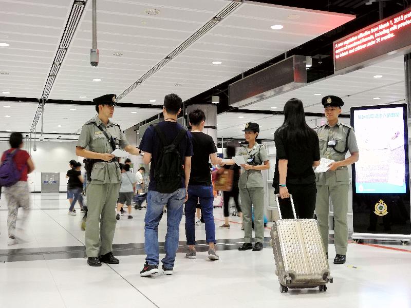 海關人員於暑假期間在邊境管制站派發傳單，提醒旅客切勿攜帶禁運或受管制物品進出香港。