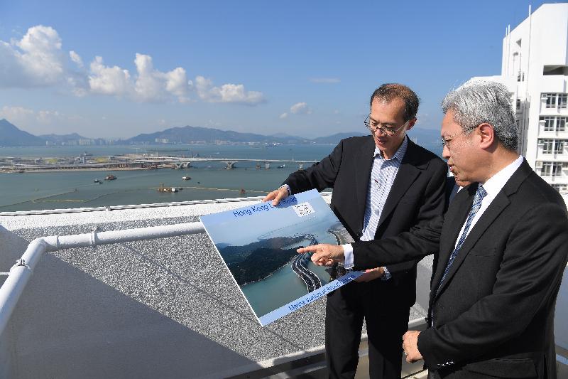 The Secretary for the Civil Service, Mr Joshua Law, today (August 8) visited Islands District and observed from height at Ying Tung Estate in Tung Chung the various infrastructure and development projects. Photo shows Mr Law (right) being briefed by a colleague of a related department on the latest situation of the Hong Kong-Zhuhai-Macao Bridge, a cross-boundary transport infrastructure project connecting Guangdong, Hong Kong and Macao.
