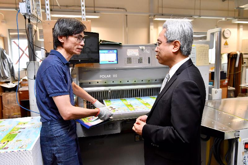 公務員事務局局長羅智光今日（八月二十日）到訪政府物流服務署。圖示羅智光（右）向印務科裝訂小組的同事了解切紙機的操作。