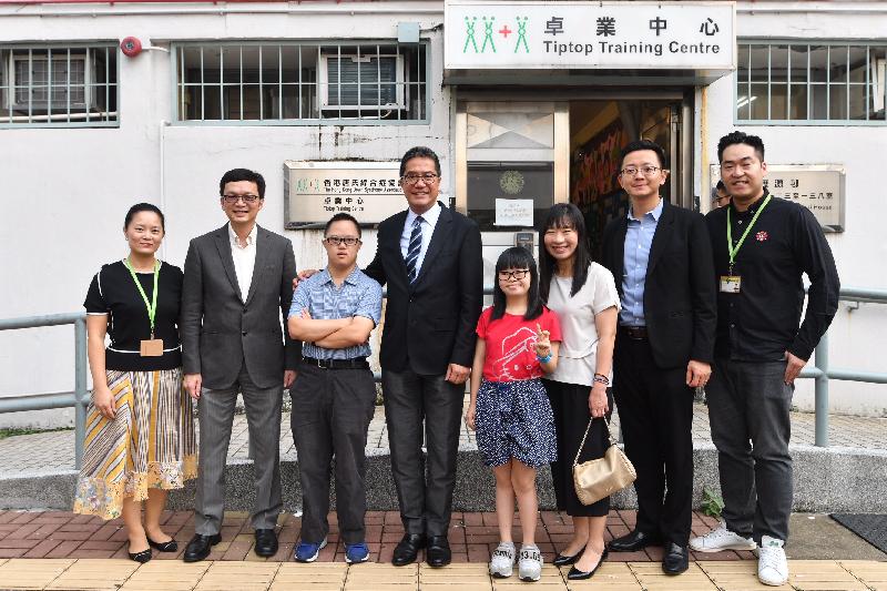 發展局局長黃偉綸今日（八月二十四日）在到訪沙田區期間，參觀香港唐氏綜合症協會卓業中心。黃偉綸（左四）和發展局副局長廖振新（左二）與中心負責人及學員合照。