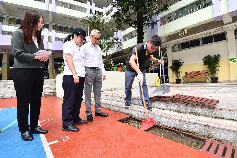 The Acting Secretary for Food and Health, Dr Chui Tak-yi (second right), visited a school in Wong Tai Sin today (August 24) to see the mosquito preventive work in the school premises before the start of the new school year. Photo shows Food and Environmental Hygiene Department staff instructing the school staff to clear refuse inside surface channels so as to prevent mosquito breeding.