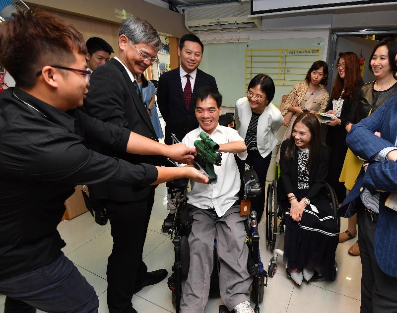 The Secretary for Labour and Welfare, Dr Law Chi-kwong, today (September 13) visited Sai Kung District and called at the wheelchair repair centre of the Direction Association for the Handicapped. Photo shows (second row, from first left) Dr Law; the Under Secretary for Labour and Welfare, Mr Caspar Tsui; and the District Social Welfare Officer (Wong Tai Sin/Sai Kung), Ms Micy Lui, being introduced to mock equipment designed by volunteers for persons with disabilities to enjoy wargaming.