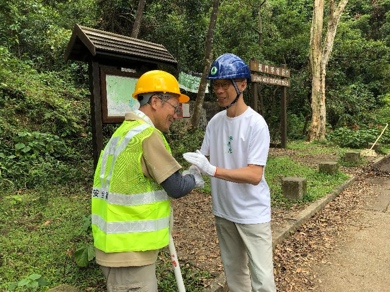 环境局局长黄锦星（右）今日（九月二十七日）到访城门郊野公园，与协助清理的义工交谈。