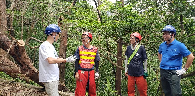 Accompanied by the Director of Agriculture, Fisheries and Conservation, Dr Leung Siu-fai (first right), the Secretary for the Environment, Mr Wong Kam-sing (first left), visited Shing Mun Country Park today (September 27), where he is pictured chatting with staff of the Agriculture, Fisheries and Conservation Department who helped with the clean up work.