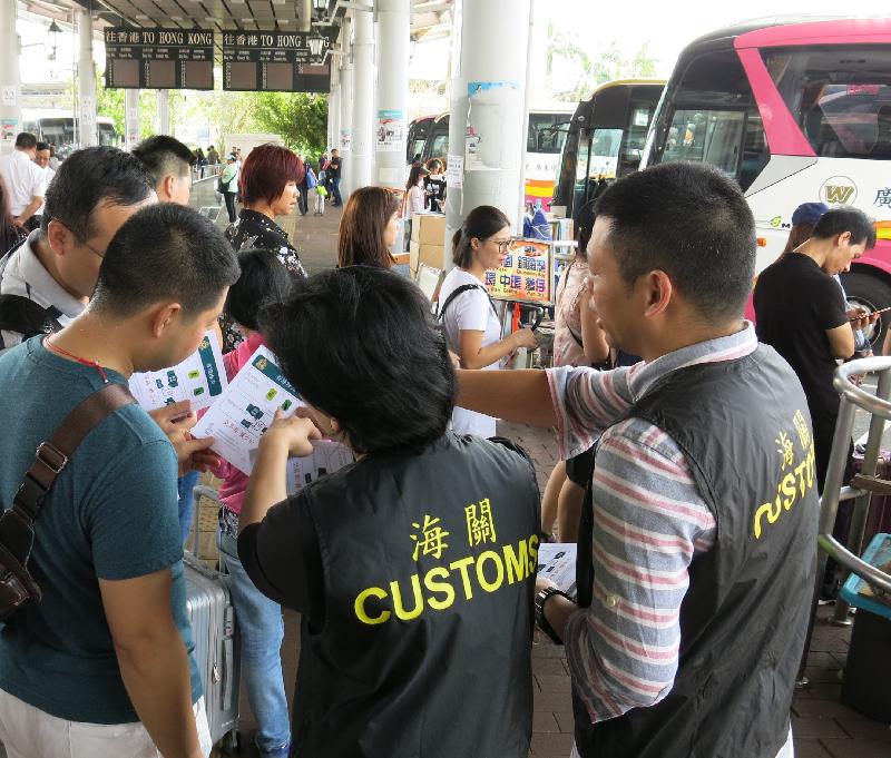 香港海关今日（九月二十八日）展开「极光」行动，在「国庆黄金周」期间加强巡查，以保障消费者。图示海关人员在过境巴士站派发提醒访港旅客精明消费的单张。