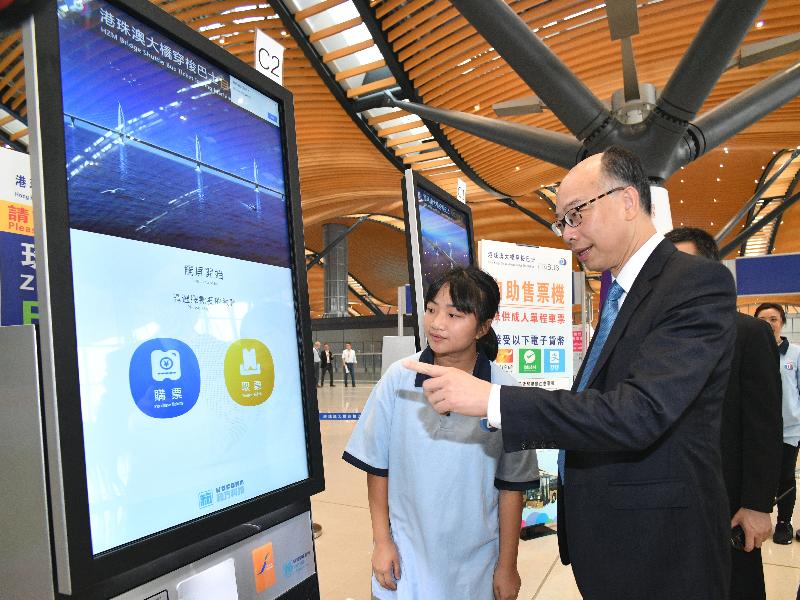 The Secretary for Transport and Housing, Mr Frank Chan Fan, today (October 24) visited the Hong Kong Port of the Hong Kong-Zhuhai-Macao Bridge to see the preparations for the commissioning of the bridge. Photo shows Mr Chan (right) learning about the operation of the shuttle bus ticket vending machine in the departure hall of the Passenger Clearance Building.