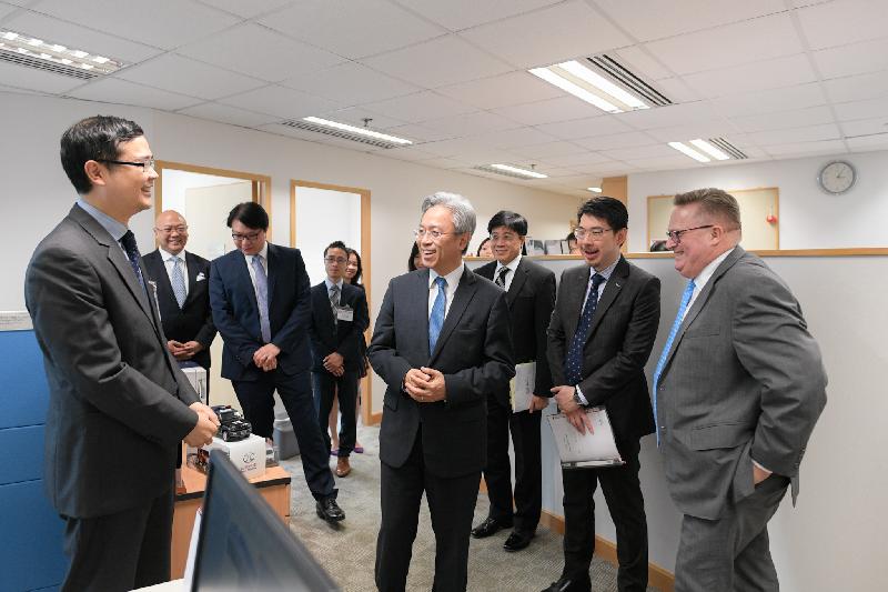 The Secretary for the Civil Service, Mr Joshua Law, visited Invest Hong Kong today (October 26). Photo shows Mr Law (centre) being briefed by a colleague of the Transport and Industrial Team on the team's work. Looking on is the Director-General of Investment Promotion, Mr Stephen Phillips (first right).