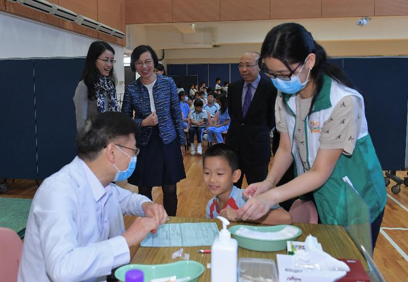 食物及衞生局局長陳肇始教授（後排中）今日（十一月五日）上午於「學校外展疫苗接種先導計劃」的外展疫苗接種活動上，陪同學童接種疫苗。