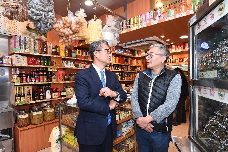 The Financial Secretary, Mr Paul Chan, this afternoon (December 12) visited several specialty shops in Kowloon City District. Photo shows Mr Chan (left) exchanging views with a business operator.