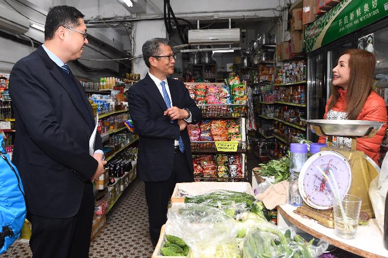 The Financial Secretary, Mr Paul Chan, this afternoon (December 12) visited several specialty shops in Kowloon City District. Photo shows Mr Chan (centre), accompanied by the District Officer (Kowloon City), Mr Franco Kwok (left), exchanging views with a business operator.
