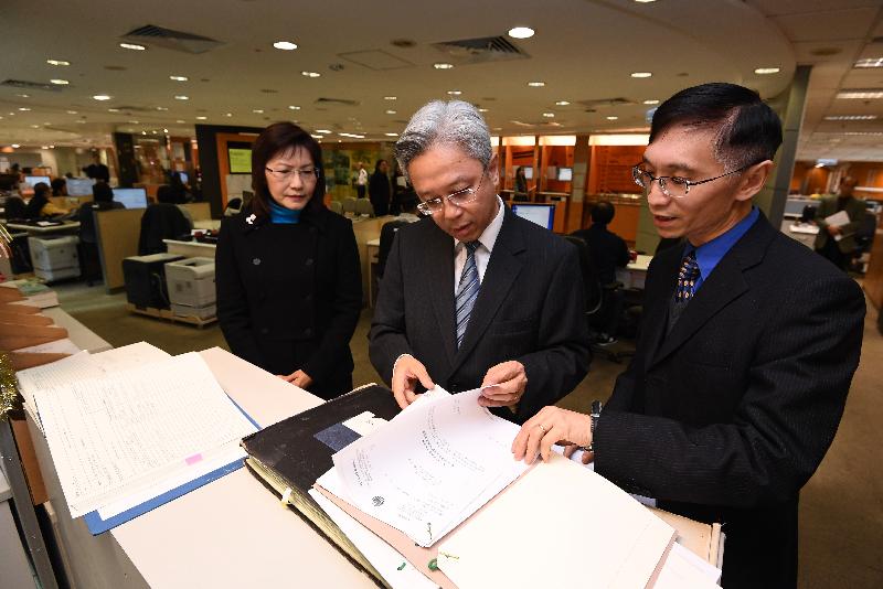 The Secretary for the Civil Service, Mr Joshua Law, visited the Land Registry today (December 14). Photo shows Mr Law (centre) browsing the owners' incorporation records kept at the Customer Centre. Looking on is the Land Registrar, Ms Doris Cheung (left).
