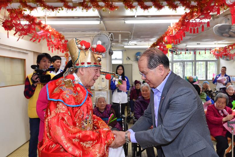 政务司司长张建宗（右）今早（二月五日）到访大埔一所护理安老院，与长者共庆新春。图示张建宗向一位装扮成「财神」的长者拜年。