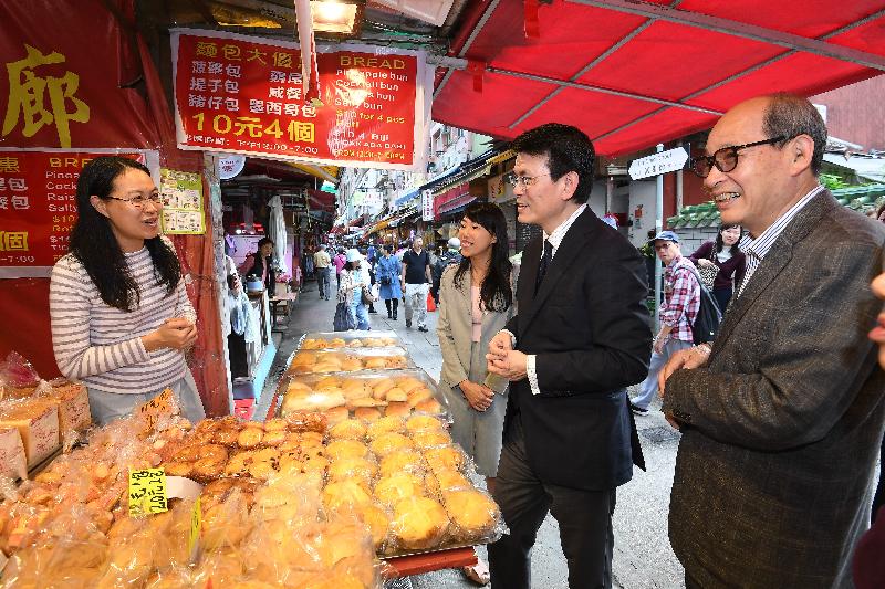 The Secretary for Commerce and Economic Development, Mr Edward Yau (second right), visited a bakery in Fu Shin Street and chatted with the shop owner during his visit to Tai Po District today (February 21). Looking on is the Chairman of the Tai Po District Council, Mr Cheung Hok-ming (first right).
