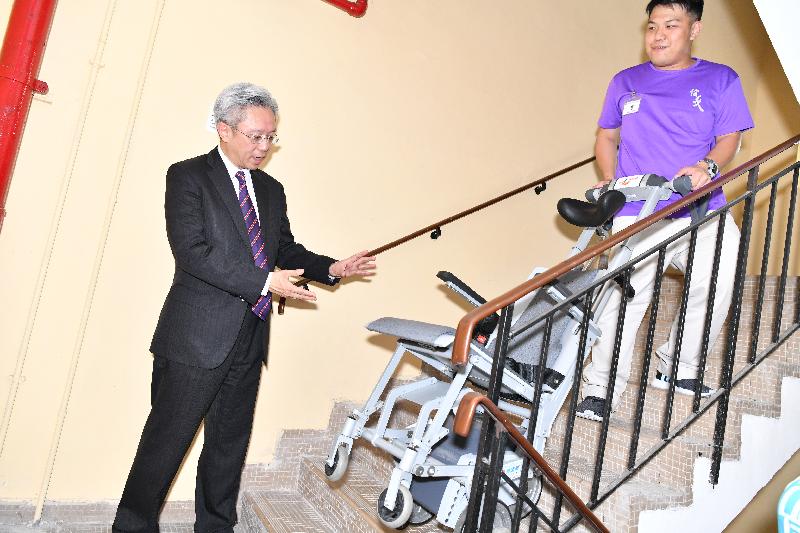 公務員事務局局長羅智光今日（四月十日）到訪屯門區。圖示羅智光（左）在基督教香港信義會社會服務部觀看人員示範操作樓梯機。