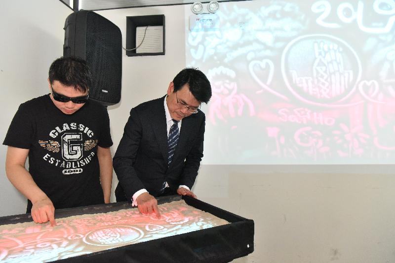 The Secretary for Commerce and Economic Development, Mr Edward Yau (right), toured the Fly the Flyover 02 and 03 near the Kwun Tong waterfront and made a sand painting with the staff there at an art workshop during his visit to Kwun Tong District today (April 12).