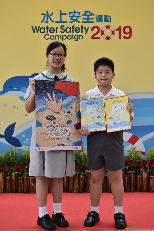 Awards for the water safety slogan and poster design competitions organised by the Leisure and Cultural Services Department and the Hong Kong Life Saving Society were presented today (June 22). Pictured with her winning entry is Tang Shuk-han (left), champion of the secondary school section in the Water Safety Poster Design Competition, and Tsang Yu-yeung (right), champion of the primary school section in the Water Safety Slogan Competition.