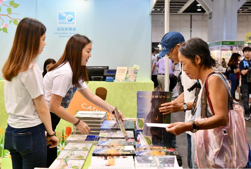 政府新闻处（新闻处）以「自然喜阅」为主题，参与今日（七月十七日）至七月二十三日举行的香港书展。图示市民在新闻处摊位阅览图文并茂的书目。
