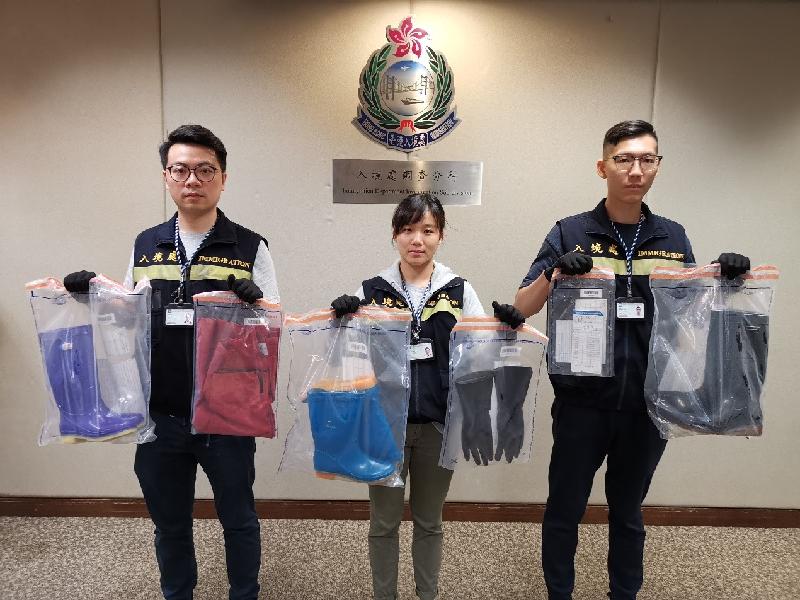 The Immigration Department mounted an anti-illegal worker operation codenamed "Twilight" yesterday (August 12) on Hong Kong Island. Photo shows officers holding items seized during the operation.