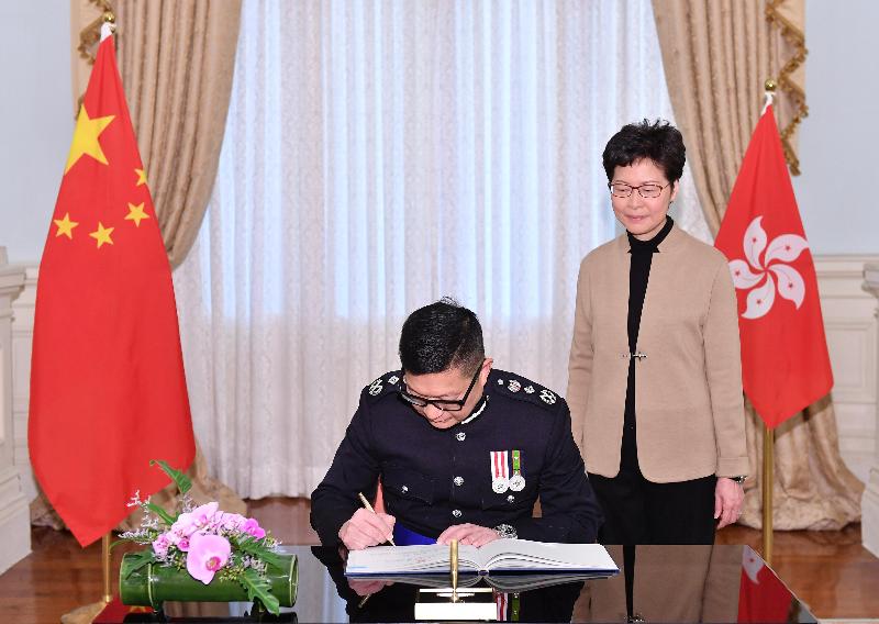 新任警務處處長鄧炳強（左）今日（十一月十九日）在宣誓後簽署誓言。