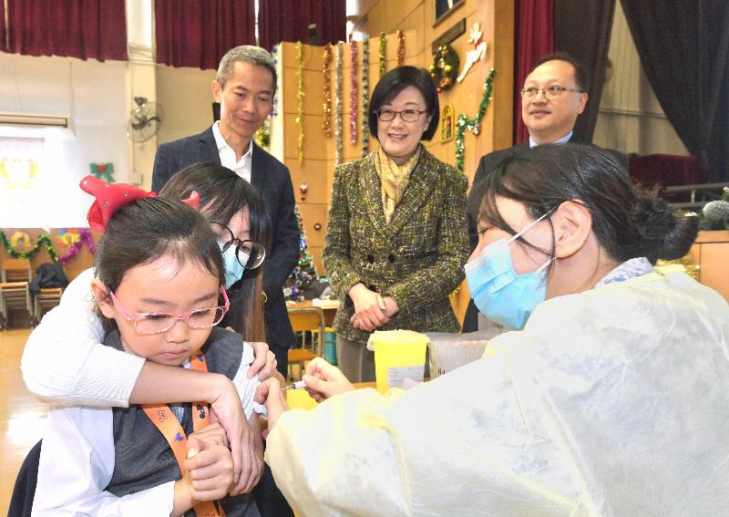 The Director of Health, Dr Constance Chan (back row, centre), and the Controller of the Centre for Health Protection of the Department of Health, Dr Wong Ka-hing (back row, left), visited Po Leung Kuk Camões Tan Siu Lin Primary School today (December 13) to observe the school outreach vaccination activity arranged by the department.
