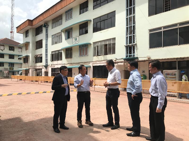 The Secretary for Development, Mr Michael Wong, today (January 14) continued his visit to Singapore. Together with the Permanent Secretary for Development (Works), Mr Lam Sai-hung (first left), and the Principal Government Engineer, Mr John Kwong (second right), Mr Wong (centre) visited a private residential project under construction. The project will feature the tallest modular integrated construction buildings in the world when completed. Photo shows Mr Wong being briefed on how five historic buildings are being preserved during the construction process. The building in the background of the picture is one of the five old buildings being preserved.
