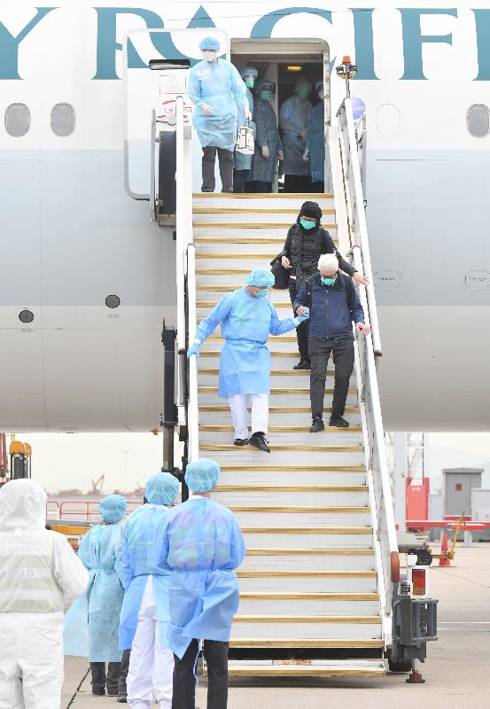 A total of 106 Hong Kong residents on board the Diamond Princess cruise ship, including the six persons who had completed quarantine at a facility in Saitama Prefecture and were permitted to leave Japan, arrived in Hong Kong from Tokyo safely this morning (February 20) on a chartered flight arranged by the Hong Kong Special Administrative Region Government. Picture shows a staff member accompanying two Hong Kong residents to alight the chartered flight.