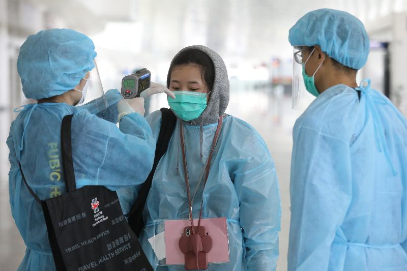 Staff members from the Department of Health measuring the body temperature of Hong Kong residents  stranded in Hubei Province before they board the chartered flight to Hong Kong at the Wuhan Tianhe International Airport today (March 4).