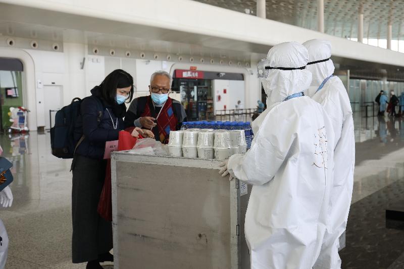 Crew members from the airline company serving refreshment, such as cup noodles and bottled water, to Hong Kong residents stranded in Hubei Province before they board the chartered flight at the Wuhan Tianhe International Airport today (March 4).