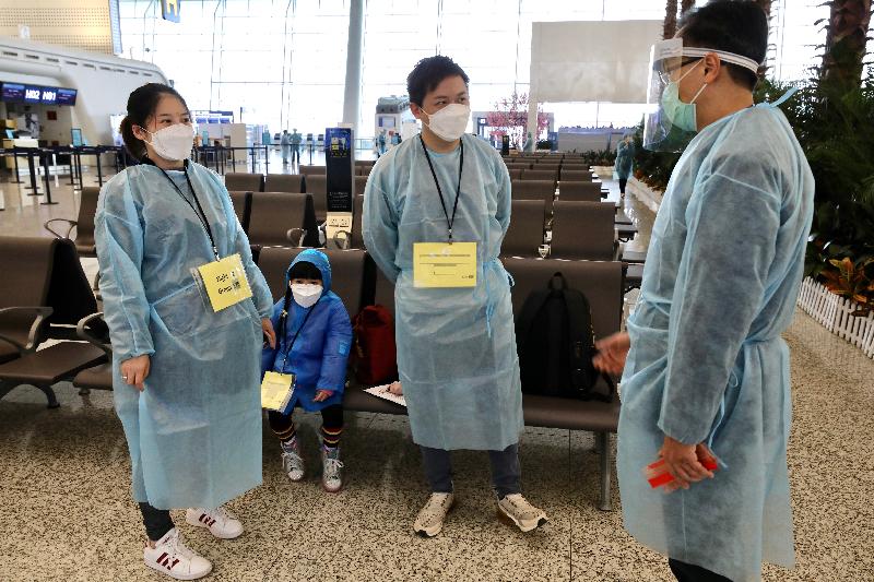 The Secretary for Constitutional and Mainland Affairs, Mr Patrick Nip (first right), sends his regards to a Hong Kong family stranded in Hubei Province, including a pregnant woman, who are waiting to board the chartered flight at the Wuhan Tianhe International Airport today (March 4).